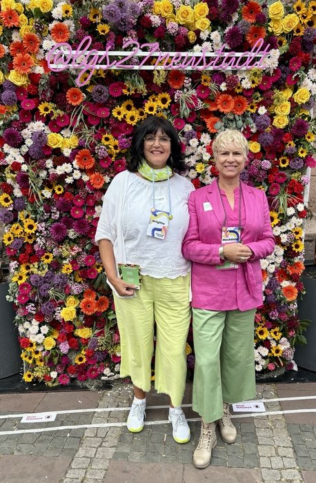 Zwei vom himmelgrün-Team vor der Blumenwand der Landesgartenschau zum RLP-Tag. 