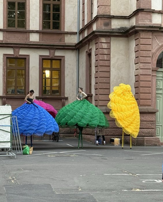 Stelzenläuferinnen mit Blütenrock ziehen sich zur Parade um.